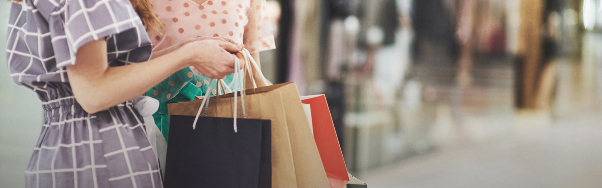 A woman holding many shopping bags outdoors with a friend